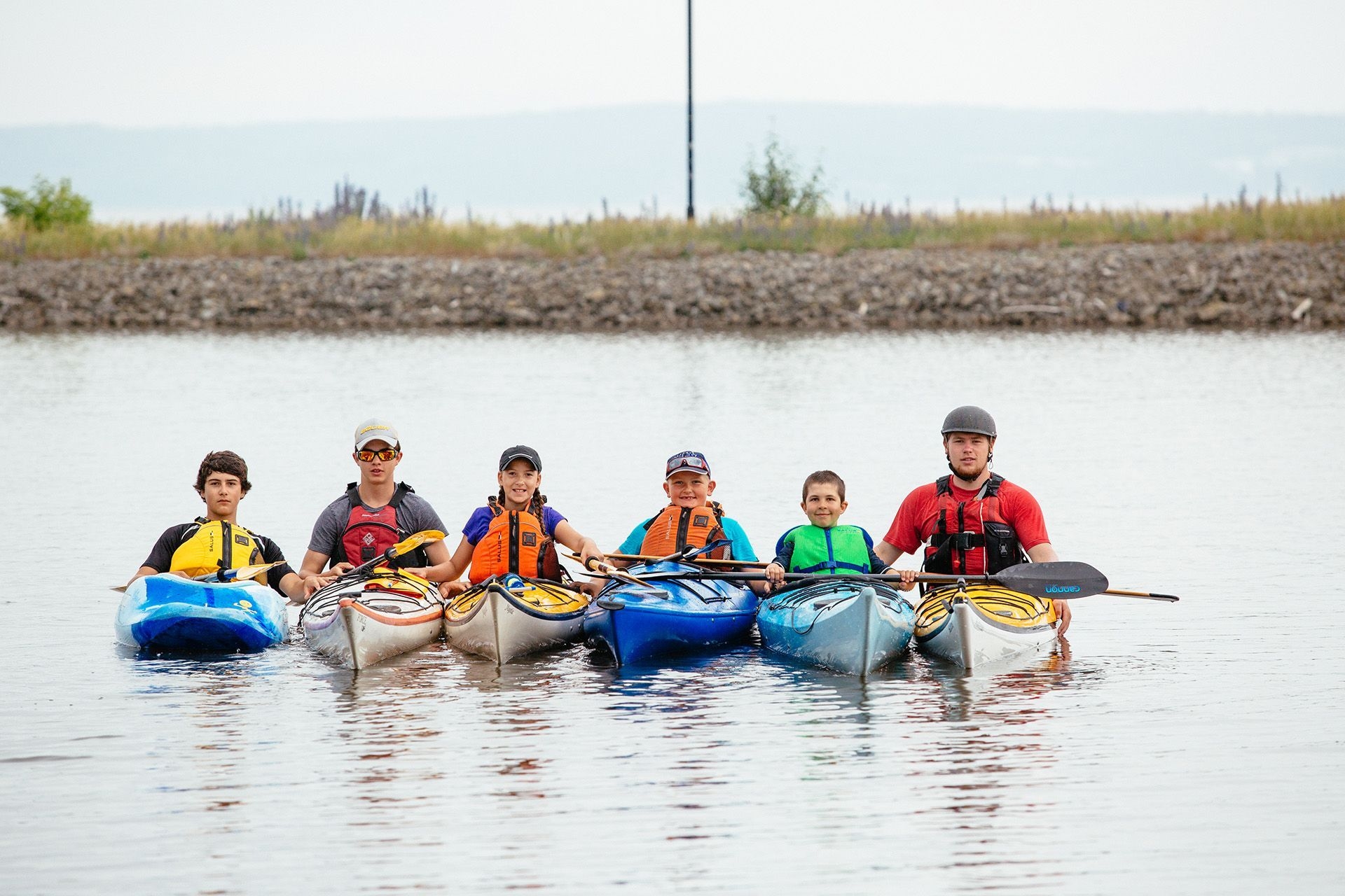 Un groupe de kayakistes pose, faisant dos au rivage.