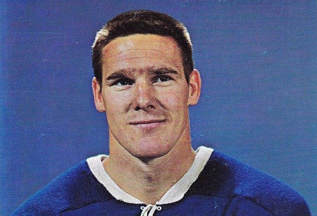 Une photo officielle de hockey de Tim Horton. Il porte un jersey bleu. 