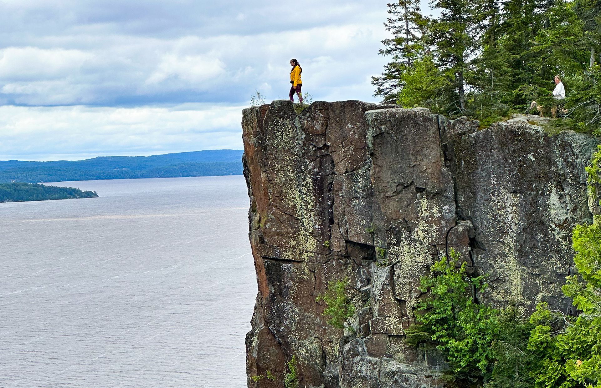 Une personne se tient au sommet de Devil's Rock, une falaise bien droite qui plonge dans le lac Temiskaming.