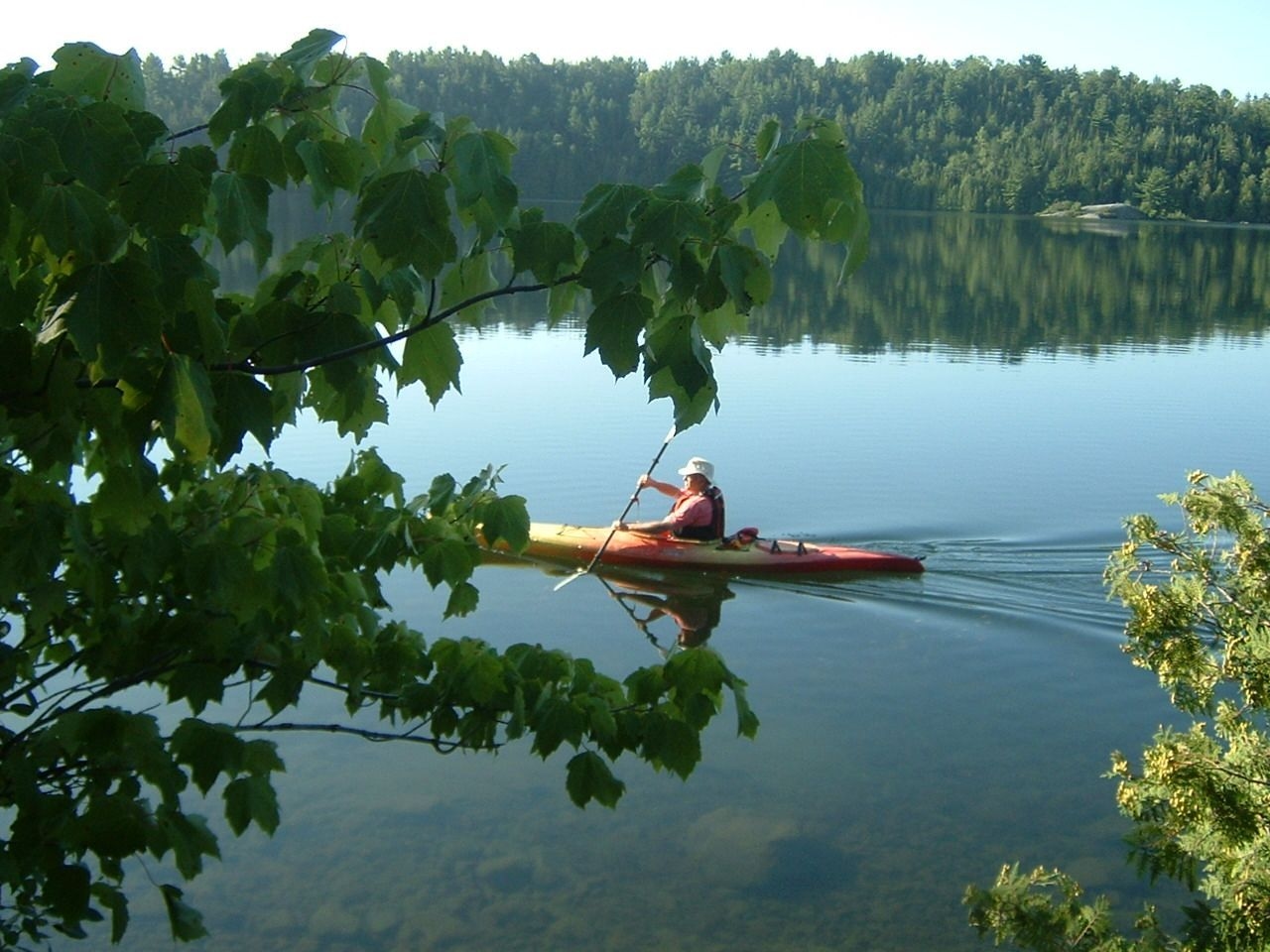Une personne faut du kayak sur un lac aux eaux calmes.