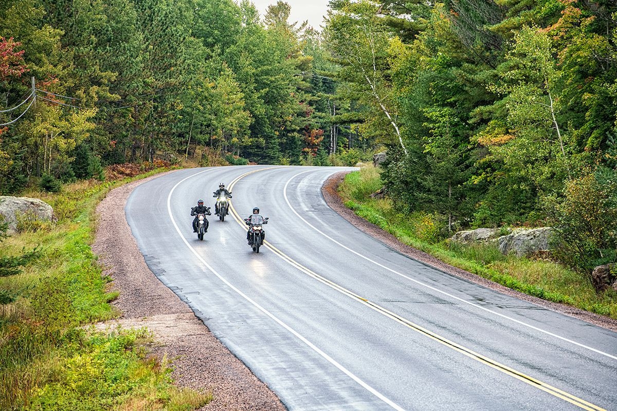 Trois motos circulent sur une route sinueuse. 