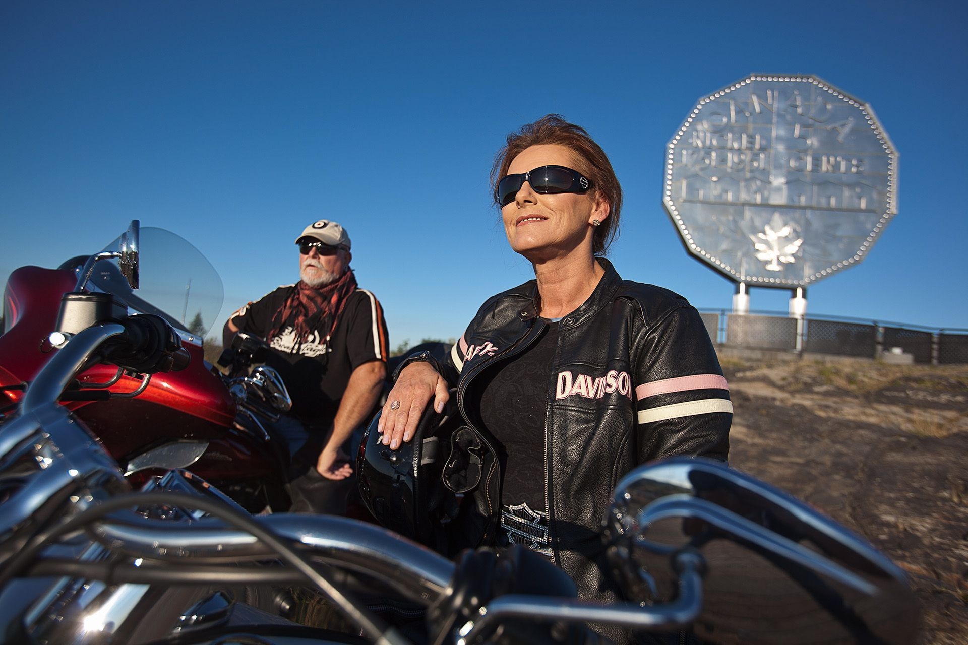 Deux personnes à moto assises devant le Big Nickel à Terre Dynamique.