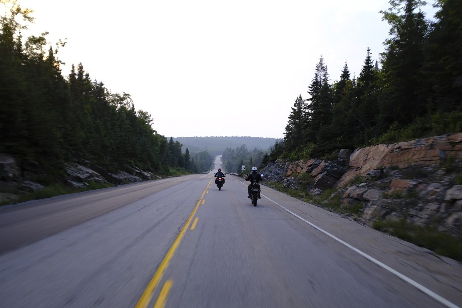 Deux motocyclettes se suivent sur une route à double voie.