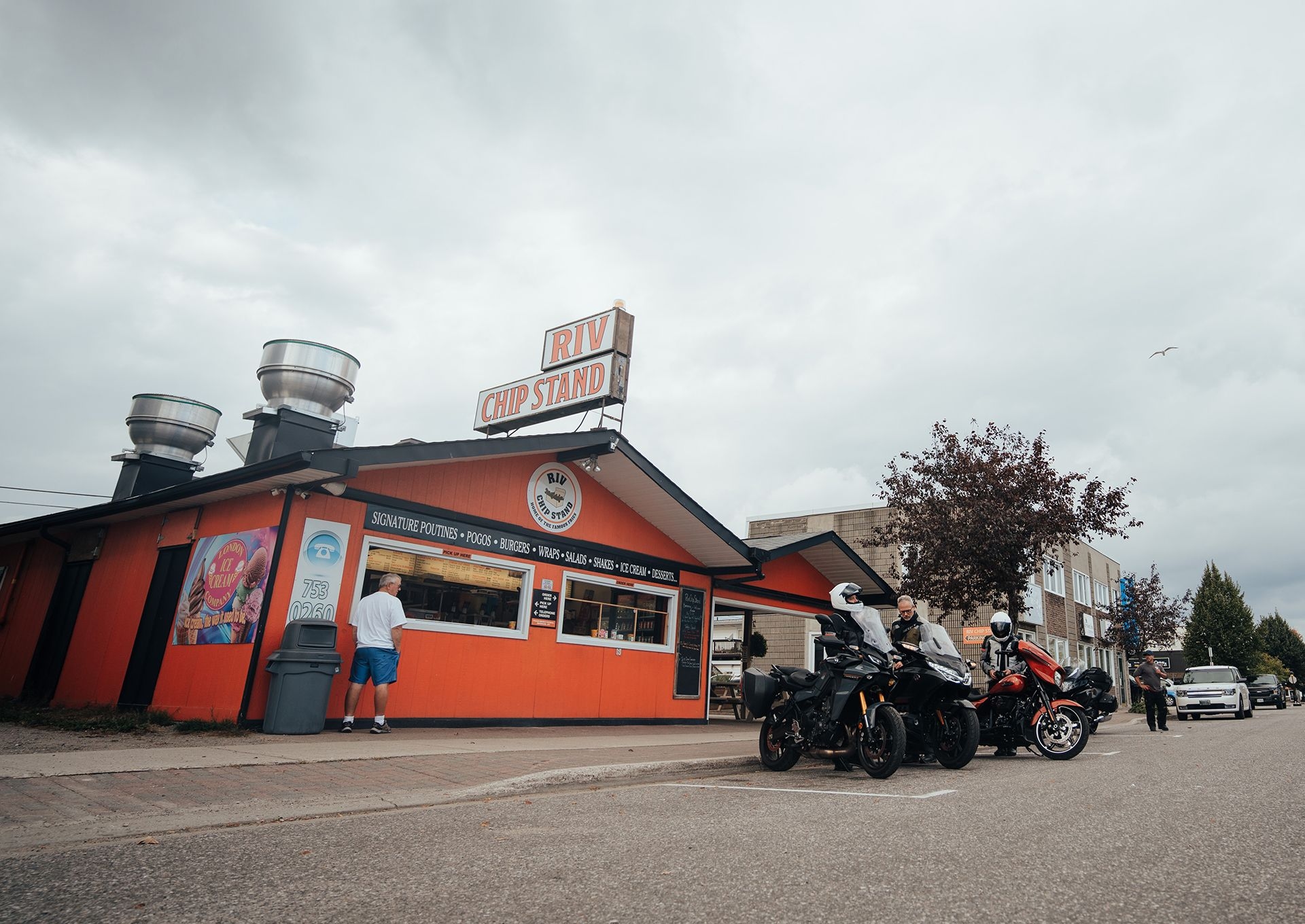 a one story orange building with two takeaway windows and a sign that says Riv's Chip Stand