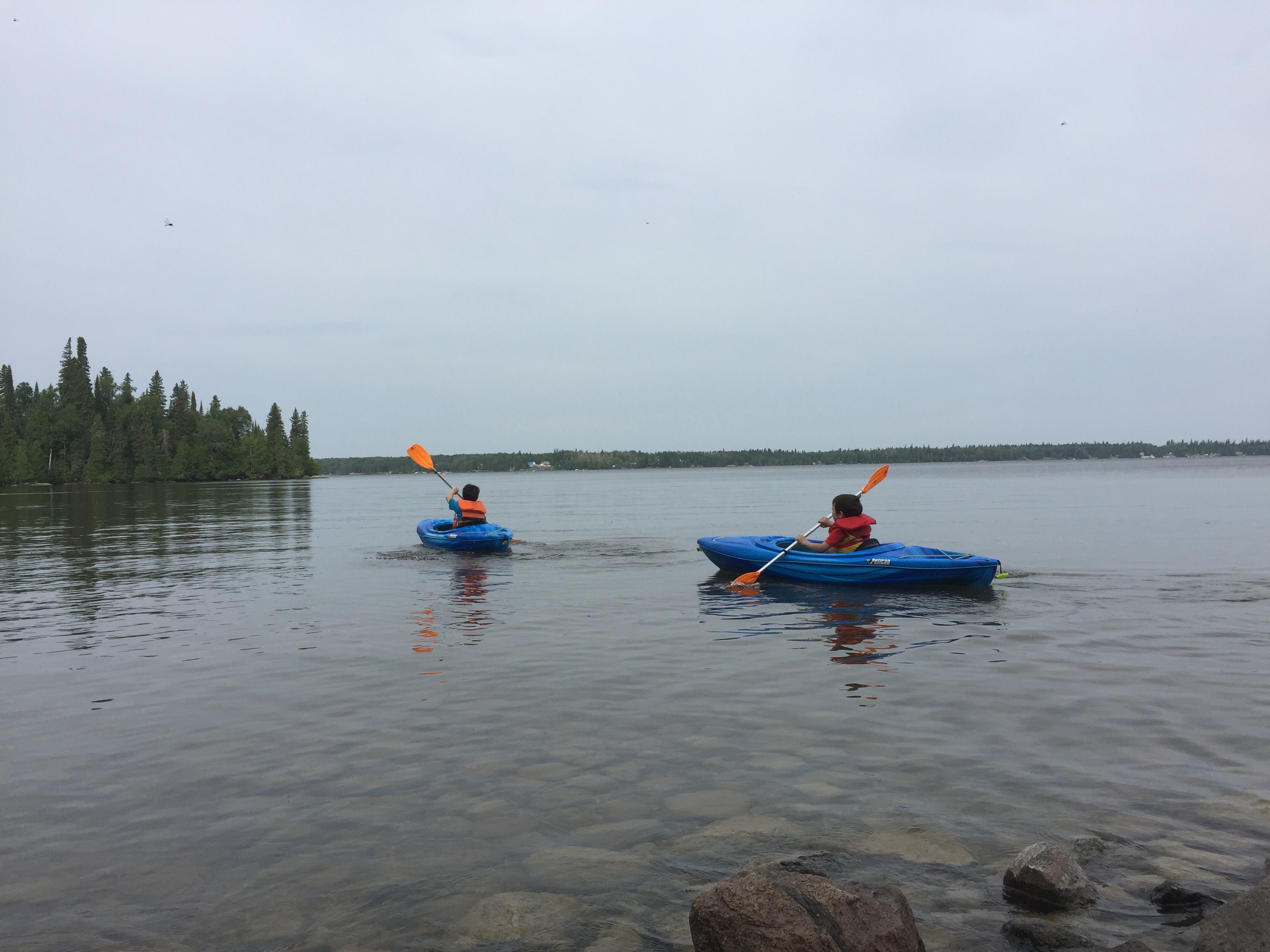 Deux enfants circulent en kayak sur le lac Rémi, près des rives du parc René-Brunelle.