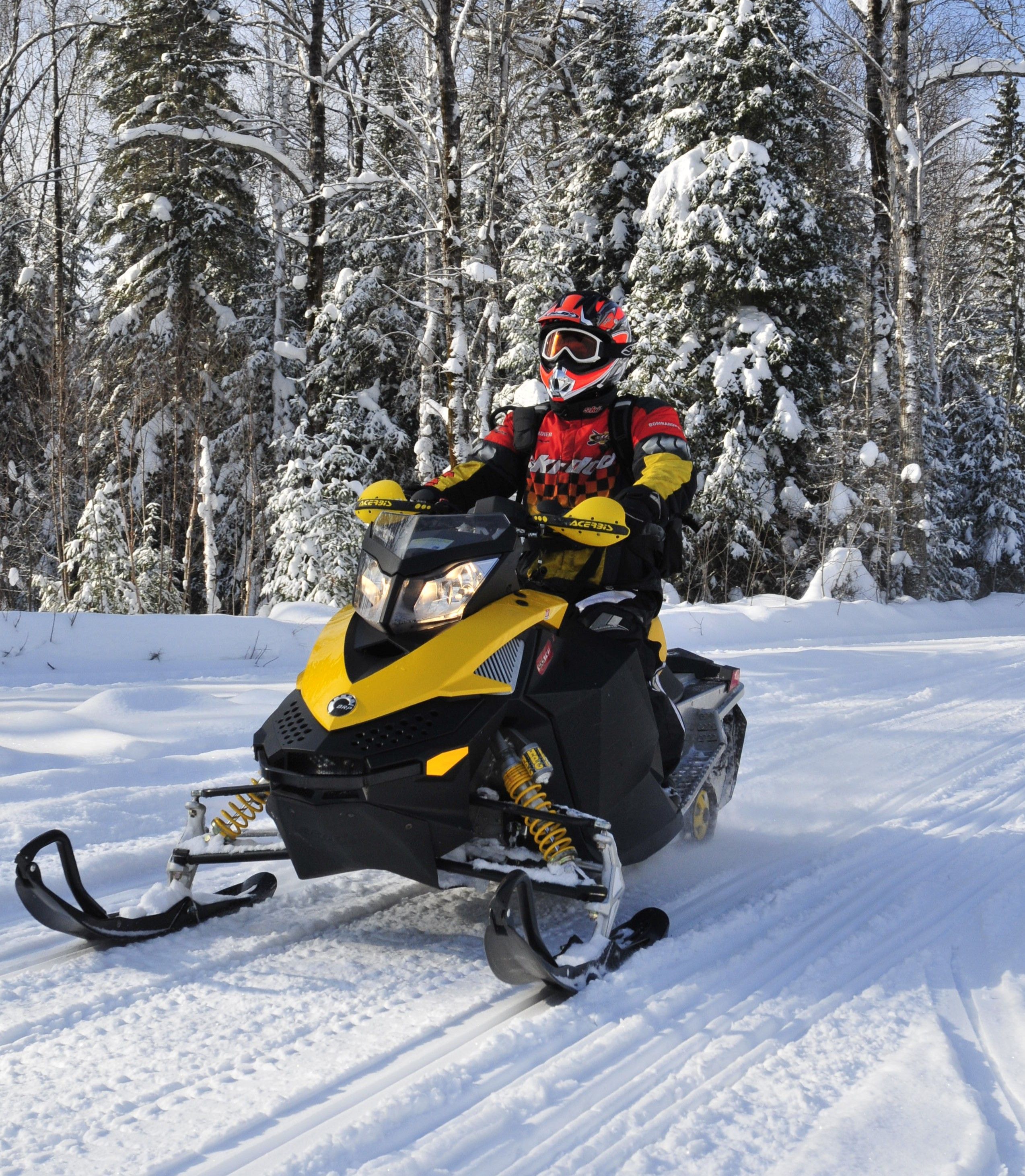 Un motoneigiste avance dans un sentier enneigé