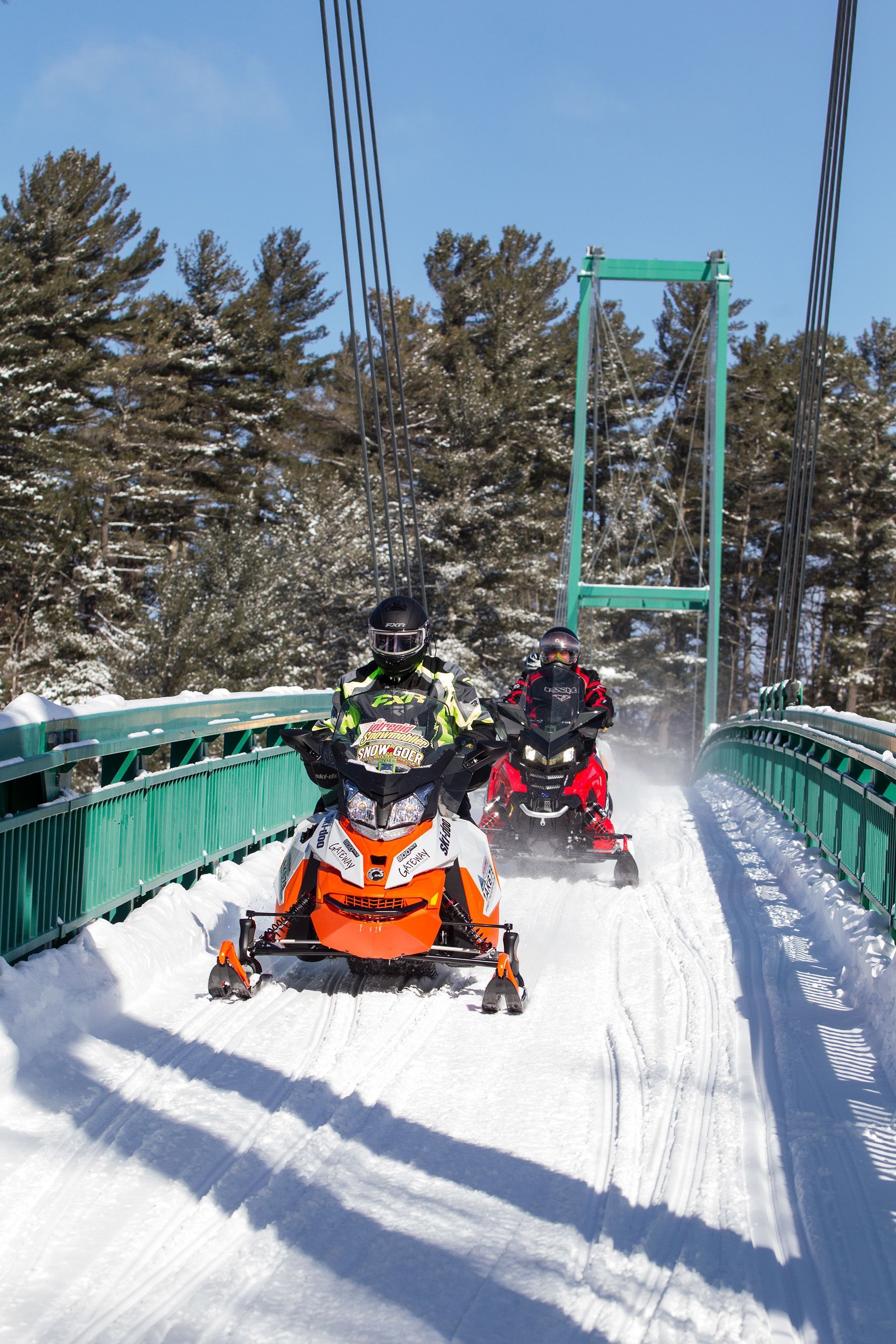 Deux motoneiges traversent le pont vert pour motoneiges qui traverse la rivière des Français.