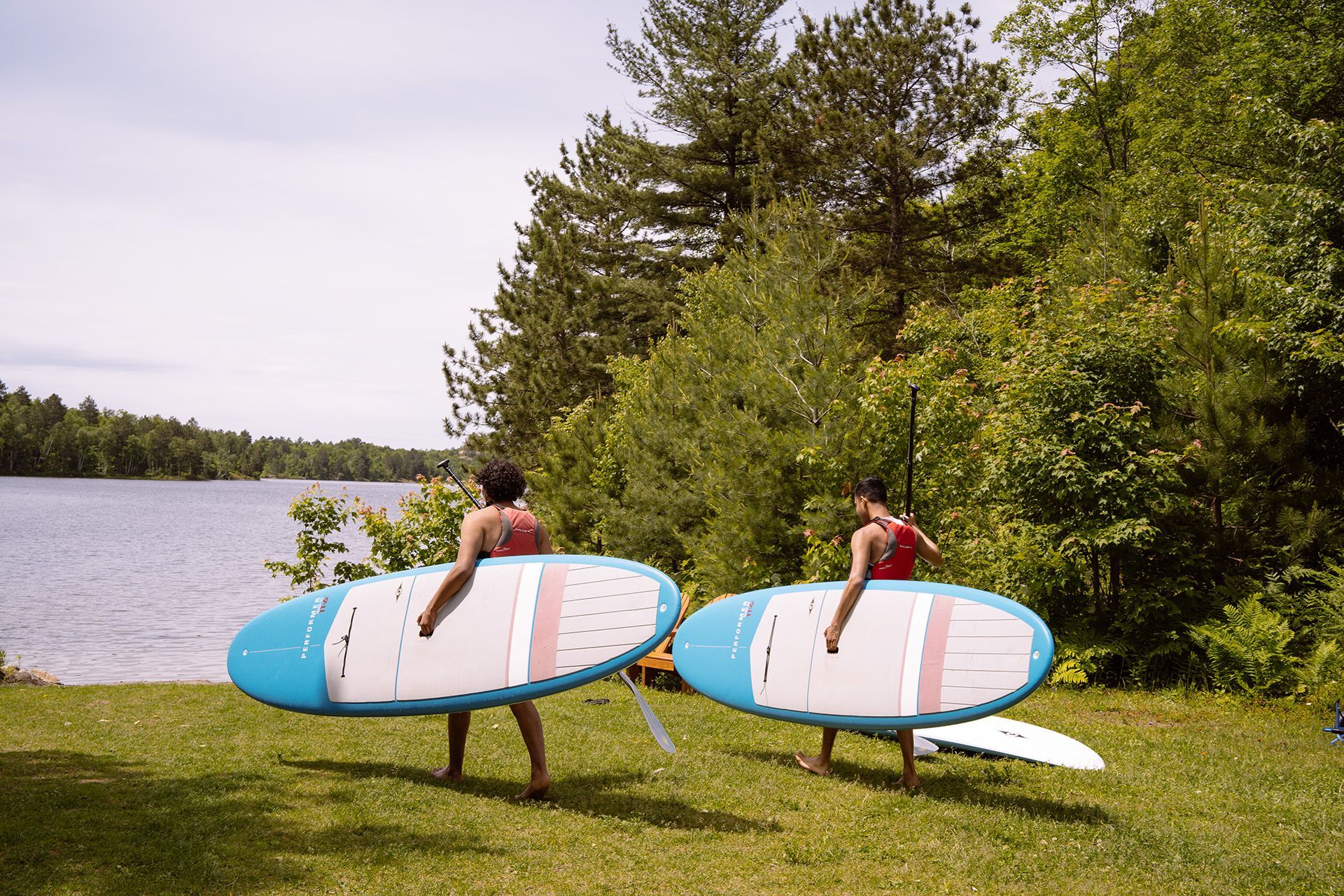 Two young men holding paddles board with the trans flag colours.